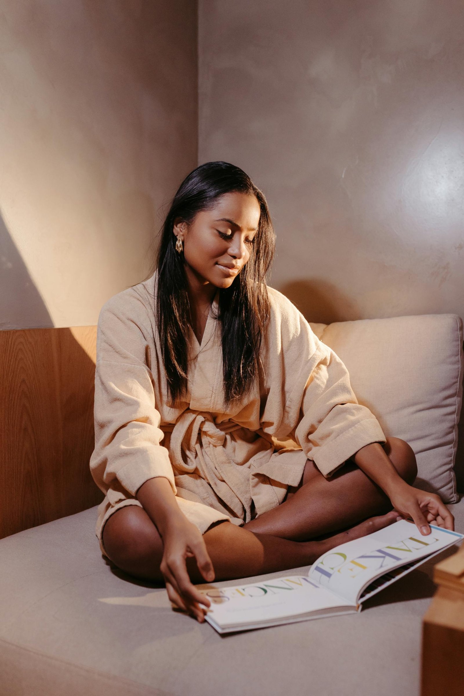 Woman wearing a bathrobe Lying on Her Hotel Bed While Reading a Catalog