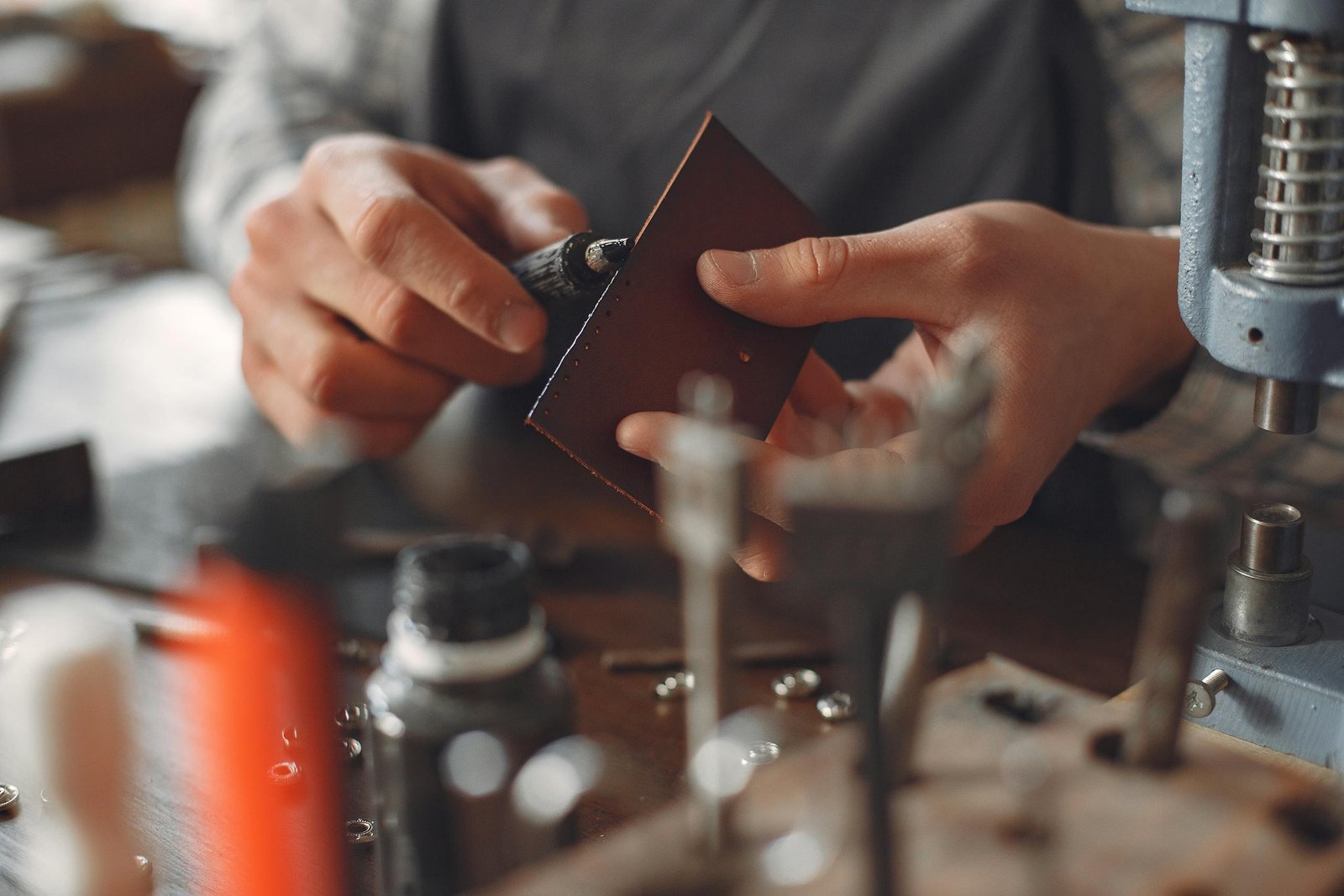 Crop artisan polishing leather edge in studio